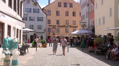 24 Temmuz 2025 'te Almanya' nın Fuessen kentindeki açık hava kafelerinde yürüyen ve oturan insanlar renkli tarihi binalarla çevrili. 