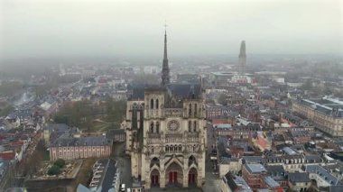 Fransa 'daki ünlü Amiens Katedrali' nin hava cephe manzarası. Karmaşık Gotik mimarisi, kırmızı kapılar, bulutlu gökyüzünün altındaki tarihi şehir manzarası. 