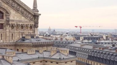 Palais Garnier 'in altın heykelleri ve Paris ufuk çizgisinin yumuşak gün ışığı altındaki dekoratif manzarası.