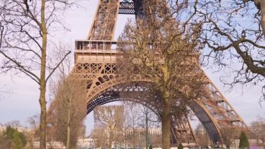 Kamera 5 Şubat 2025 'te Paris' te çıplak kış ağaçları tarafından çerçevelenen Eyfel Kulesi 'nin tabanından yukarı doğru eğiliyor. 