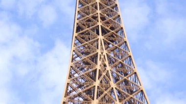 Kamera Eyfel Kulesi 'nin tepesinden Paris' te gün ışığında açık mavi gökyüzüne karşı tam demir yapıyı gösteriyor.