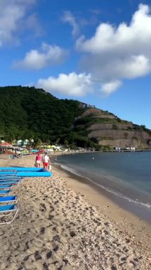 29 Temmuz 2025 'te Karayip Denizi' nde berrak mavi gökyüzünün altındaki yemyeşil tepelerin desteklediği okyanusa bakan boş şezlonglu huzurlu tropikal plajlar.