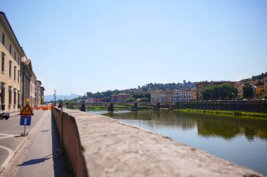 Arno Nehri 'nin kıyısındaki sessiz cadde köprüye ve renkli binalara açılıyor Florence.