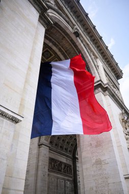 Paris 'teki Zafer Takı' nın altında dalgalanan Fransız bayrağı ulusal gurur ve mirası simgeliyor.