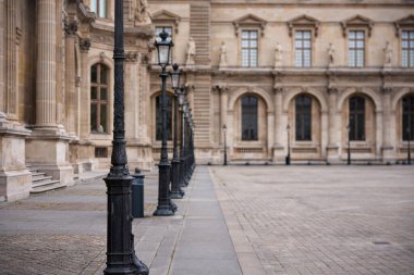 Paris 'teki Louvre Müzesi' nin avlusunda tarihi mimari ve zarif siyah sokak lambaları.