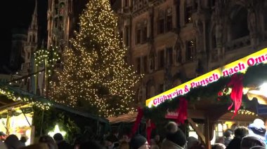 14 Aralık 2024 'te Münih' te Marienplatz 'daki Noel pazarında büyük aydınlatılmış ağaç tezgahları ve arka planda tarihi New Town Hall 