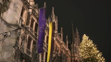 14 Aralık 2024 'te Münih Yeni Belediye Binası önünde AB ve Bavyera bayraklarıyla aydınlatılmış Noel ağacı 