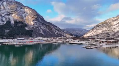 Norveç 'te tekneleri ve karlı dağ yansımaları olan manzaralı kış limanı