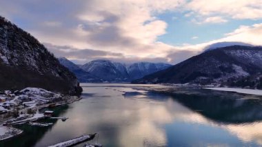 Sakin suları ve kenetlenmiş tekneleri olan karlı fiyort.