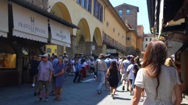 4 Temmuz 2025 'te Floransa' da Ponte Vecchio 'da beyaz elbiseli bir kadın ve turist kalabalığı kuyumcuların arasında dolaşıyordu. Sadece editör kullanımı