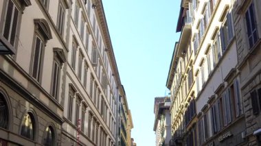 4 Temmuz 2025 'te Floransa İtalya' da açık mavi gökyüzü altında geleneksel panjurlu binalarla dolu tarihi merkezdeki dar cadde manzarası. Sadece editör kullanımı