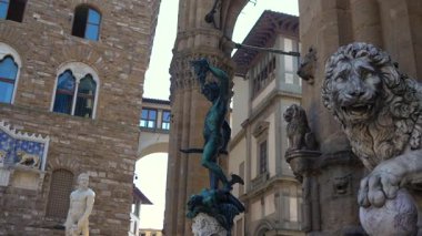 Cellini 'nin Loggia dei Lanzi' deki Bronz Perseus heykeli ve Floransa 'nın arka planında Palazzo Vecchio. Ilık bronz ve taş kontrastı açık mavi gökyüzü. Sadece editör kullanımı.