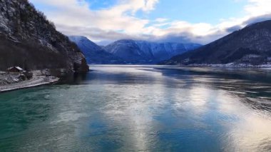 Turkuaz yansıtıcı su ve dağları olan manzaralı kış fiyordu
