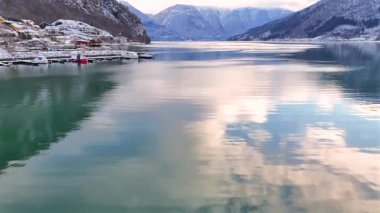 Tekneleri, karlı dağları ve durgun suları olan manzaralı kış fiyordu.