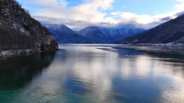 Durgun su ve karla kaplı yamaçlı fiyort manzarası