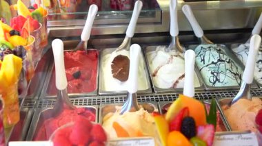 Geleneksel İtalyan dondurması seçimi. Bir şehirdeki bir dükkanda markalı etiketleri gösteren soğutulmuş cam tezgahın içinde taze meyve parçalarıyla süslenmiş. Floransa 4 Temmuz 2025