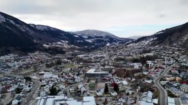 Karla kaplı evler, dolambaçlı yollar ve vadide yuva yapmış kış dağlarının bulunduğu Sogndal kasabasının insansız hava aracı manzarası.. 