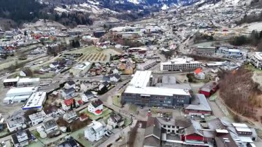 Sogndal Vadisi 'nin insansız hava aracı manzarası karla kaplı çatıları, kıvrımlı yolları ve bulutlu bir gökyüzünün altındaki kış dağlarını gösteriyor.. 