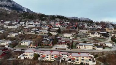 Renkli evler, dolambaçlı yollar ve çatıları ve zemini kaplayan hafif kış buzları içeren Sogndal yamaçlarının insansız hava aracı görüntüsü. 