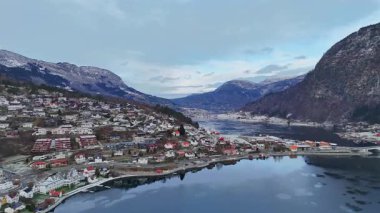 Sogndal 'ın kış manzarası. Renkli dağ evleri, karlı dağlar ve sakin fiyort üzerindeki köprü.