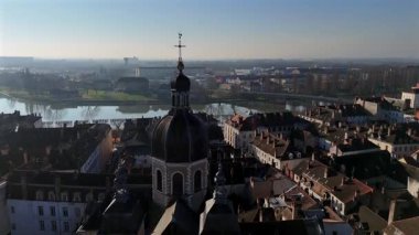 Drone aerial top view of cathedral in Chalon sur Saone France with domed roof and twin towers surrounded by dense old town rooftops and narrow streets near the Saone river in morning light