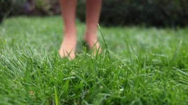 Feet of little kid stepping on lawn outdoors