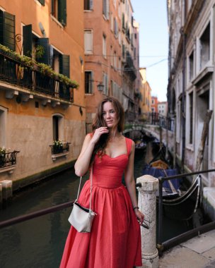 Venedik Kanalı 'nda poz veren kırmızı elbiseli genç kadın.