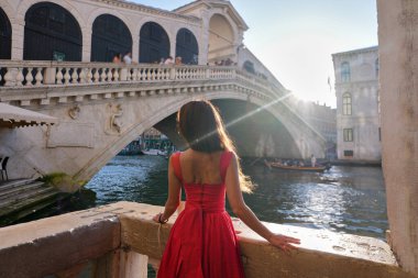Kırmızı elbiseli genç kadın Rialto Köprüsü Venedik 'e bakıyor.