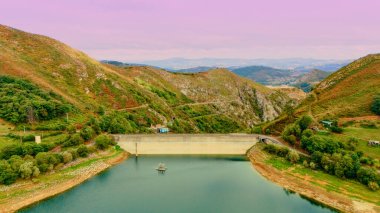 Yeşil tepeler ve uzak dağ yamaçlarıyla çevrili göl
