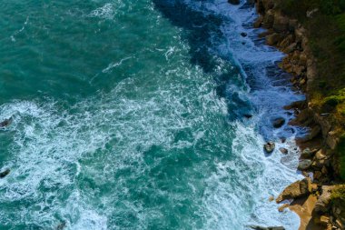 Turkuaz su ve kayalarla kaplı bir deniz manzarası.