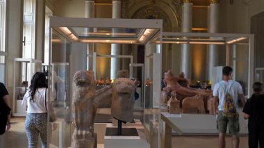 Ziyaretçiler, 1 Haziran 2025 'te antik heykeller ve dekoratif iç mimari eserlerle Paris' te büyük bir müze salonunda yürüyorlar. Sadece editör kullanımı.