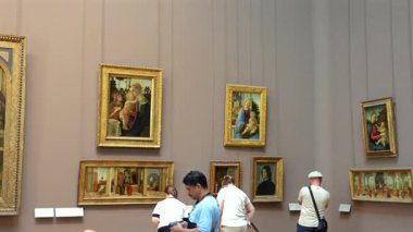 Rönesans ve ortaçağ resimlerini 1 Haziran 2025 'te bir müze galerisinde sergilenen altın çerçevelerle izleyen ziyaretçiler. Sadece editör kullanımı.