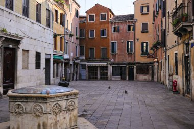 Renkli İtalyan evleri ve taş çeşmesi olan sessiz, boş bir avlu.