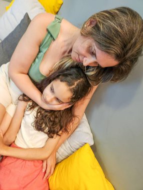 Bir anne kızını kollarında tutarak teselli ediyor.