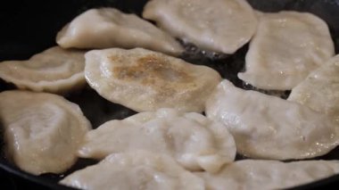 Yakından bakıldığında, yağda tavada kızaran Rus pierogisinin buharı yavaşça havaya yükseliyor..