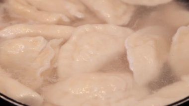 Pierogi 'nin Yakın Çekimi Sıcak, Yumuşak Mutfak Işığıyla aydınlatılan Buharlı Suda Nazikçe Kaynıyor 