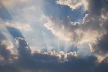 Sun rays breaking through dramatic clouds in the sky during daytime clipart