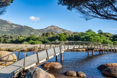 Arka planda Oberon Dağı 'nın bulunduğu gelgit nehri manzaralı bir tahta köprü ile kaplıdır. Köprü durgun suyun üzerinde kavis çiziyor, kıyı şeridini diğer tarafa bağlıyor.