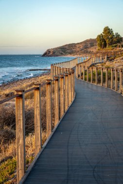 Sahilde kıyı şeridi boyunca uzanan manzaralı bir sahil yolu, sakin bir gezinti için bir yol sunuyor. Sakin atmosfer sahil boyunca yürümek için mükemmel bir ortam yaratıyor..
