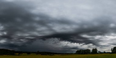 Fırtına bulutlarının gerçeküstü bir oluşumu Litvanya çayırlarının üzerinde gökyüzüne yayılıyor. Alçak, karanlık bulut tabanı ve gökyüzündeki kayan desenler bu sahneye güçlü ve diğer dünyalardan gelen bir varlık veriyor..