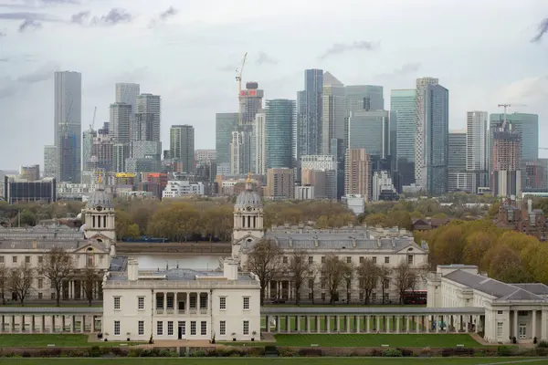 Londra 'nın mimari bir manzarasında ön plandaki klasik Kraliyet Donanma Koleji binaları ile Kanarya Rıhtımı' nın yükselen modern gökdelenleri arasındaki katı tezat gözler önüne seriliyor..