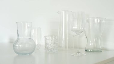 Minimalist tasarım ve zarafeti vurgulayan el değmemiş beyaz bir yüzeyde sergilenen cam bir koleksiyon. Cam vazoların ve sürahilerin berrak ve temiz çizgileri modern ve sofistike