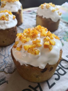 A close up view of Easter bread topped with white icing and candied orange zest, highlighting its detailed texture and golden baked surface. The image reflects the joy of festive baking and culinary clipart