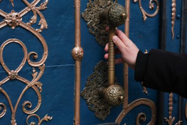 A hand grasping an ornate brass door handle on a vintage door. This close-up emphasizes heritage, timeless elegance, and the charm of traditional craftsmanship. Perfect for concepts of discovery clipart