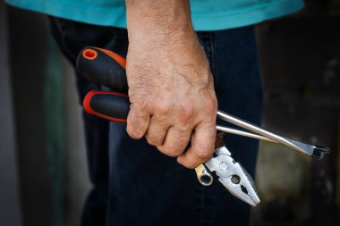 El ele tutuşan bir pense, bir tornavida ve diğer aletler, elle çalışmayı ya da tamir etmeyi sembolize ediyor. İnşaat, DIY ve işçilikle ilgili içerik için mükemmel.