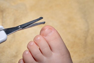 Küçük bir tırnak makası gibi bir çocuğun elini dikkatlice kes. Görüntü, çocuklar için hijyen ve güvenliği vurguluyor. Çocuk bakımı, hijyen rutinleri veya