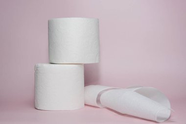 Pastel pembe arka planda yaratıcı bir şekilde düzenlenmiş tuvalet kağıdı koleksiyonu. Minimalist düzende hijyen, temizlik ve günlük ihtiyaçlar vurgulanıyor. Kişisel bakım reklamları için ideal.