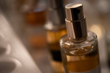 Altın püskürtme başlıklı cam parfüm şişesinin yakın çekimi zarafet ve detayı yakalıyor. Güzellik, lüks ve koku temalı görseller için ideal.