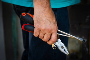 El ele tutuşan bir pense, bir tornavida ve diğer aletler, elle çalışmayı ya da tamir etmeyi sembolize ediyor. İnşaat, DIY ve işçilikle ilgili içerik için mükemmel.