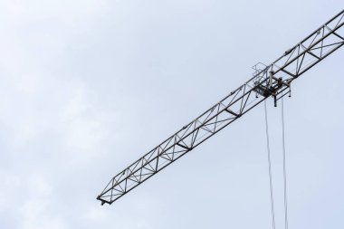 A minimalistic image of a construction crane arm extending into the pale blue sky. The clean lines and modern aesthetic highlight industrial progress and urban development. Suitable for use in clipart